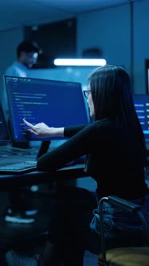 Asiatische junge IT-Spezialistin codiert auf dem Desktop im dunkelblauen Serverraum. Programmiererpunkte