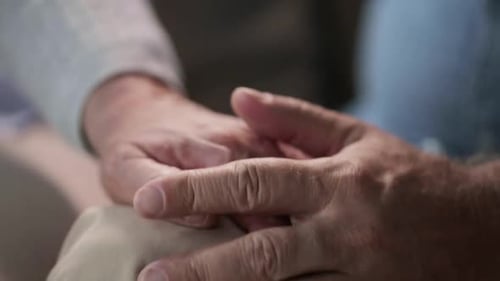Senior Couple Holding Hands Tenderly Indoors