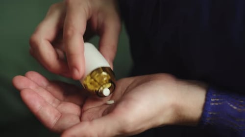 Woman Holds Bottle and Pills in Hand