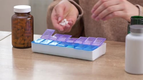 Sorting Pills Into Pill Organizer on Table