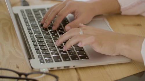 Woman Typing on Laptop at Wooden Desk