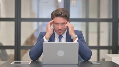 Stressed Businessman Working on Laptop in Office