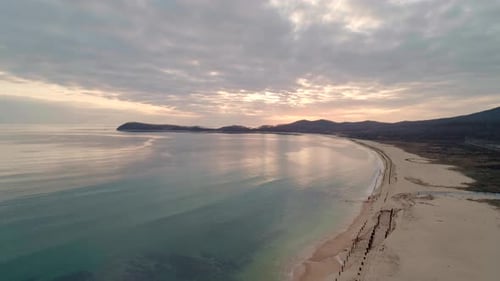 Aerial View of Beach with Calm Transparent Sea Water and Sky Reflection at Sunset Camera Moves Up