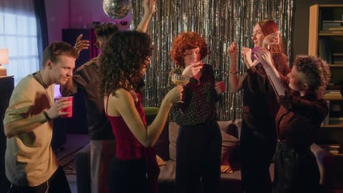 Group of Energetic Young Friends Dancing and Drinking under Flickering Lights