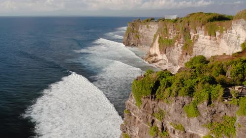 Person Standing on Cliff Next to Beach and Ocean Uluwatu in Bali Indonesia