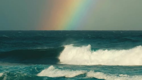 Hawaiian seascape. Waves break on the Hawaiian shore with rainbow on the background