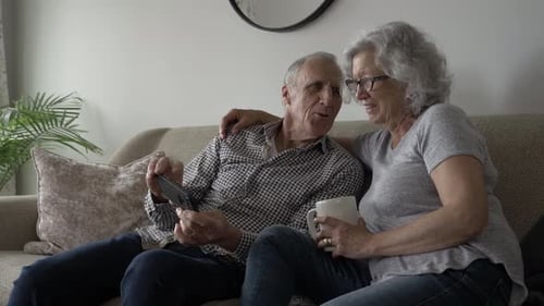 Senior Couple Relaxing on Couch Looking at Phone