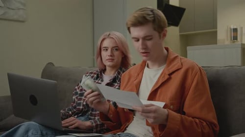 Couple on Couch Reviewing Finances with Laptop