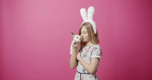Girl with Bunny Cuddling on Pink Background
