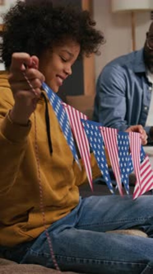 Child and Adult Stringing American Flags Together