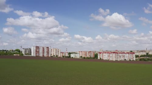 Drone View Establishing Shot Over Green Field Located Near Modern City District with Contemporary