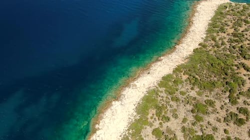 El mar azul claro, la costa rocosa y los arbustos verdes forman una costa impresionante bajo un cielo brillante y soleado.
