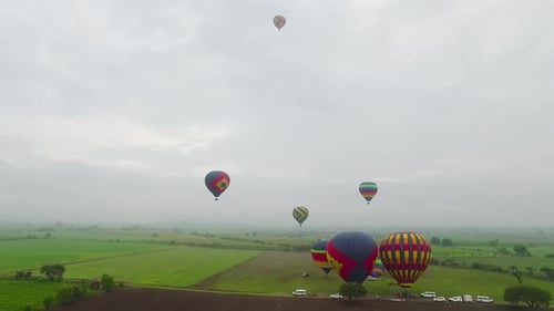 Luftaufnahme von Heißluftballons, die über Feldern schweben.