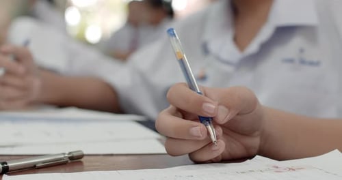 Plan découpé pendant que les étudiants en uniforme blanc écrivent les réponses sur leurs papiers