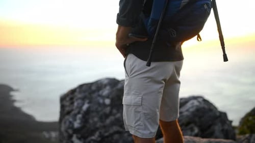 Man, hiker and backpack on mountain top, view and sunset over ocean, climber and hiking