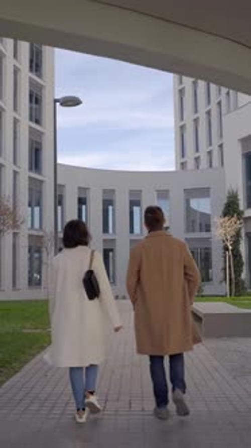 Female and Male Doctor Colleagues Going Out From Hospital Shot Followed By the Camera