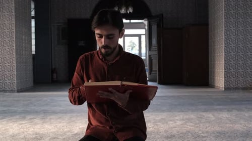 Un musulman dans une mosquée lisant le Coran, le livre religieux de l'islam, le livre sacré de l'islam est écrit