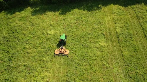 Vue aérienne d'un tracteur dans un champ qui tond l'herbe