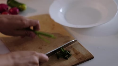Chopping Green Vegetables with Knife on Cutting Board