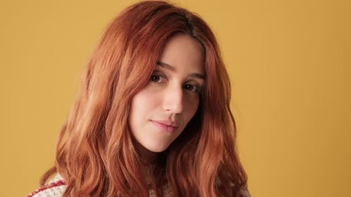 Close-up of girl looking at camera on yellow background in studio