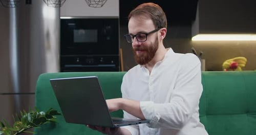 Attraktiver Mann, der sich mit Softwaretechnik beschäftigt und von zu Hause aus arbeitet und sich auf Laptops konzentriert
