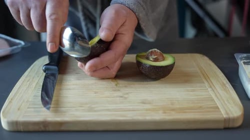 Adult Using Spoon to Scoop Out an Avocado
