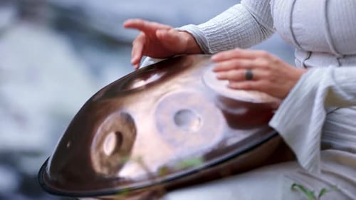 A Serene Moment Captured Playing the Handpan By Tranquil Waters Showcasing the Beauty and Artistry
