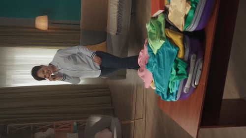 Vertical Video of a Brunette Middleaged Woman Having a Call on the Background While Packing a