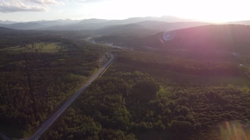 Car driving on highway through hilly area towards mountains in sunset
