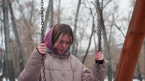 Young Lady Stepping on Swing in Snowy Park