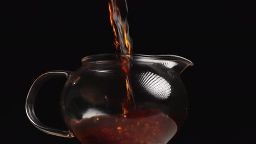 Pouring Tea Into a Clear Glass Teapot