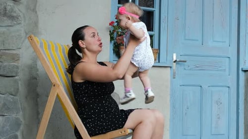 Cheerful Mother Playing with Baby on Terrace
