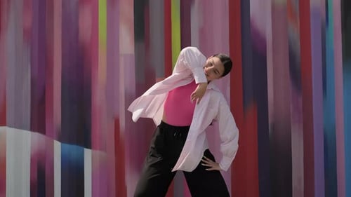 Attractive Young Woman Dancing in Front of Wall