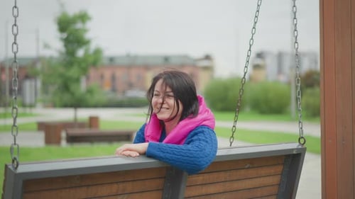 Woman relaxing on a swinging bench in a park