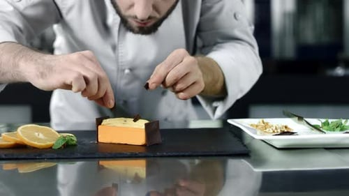 Chef hands gently putting chocolate on cake in slow motion at kitchen restaurant