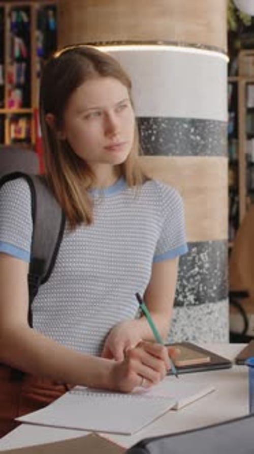 Young Female Student Writing Down Ideas in Library