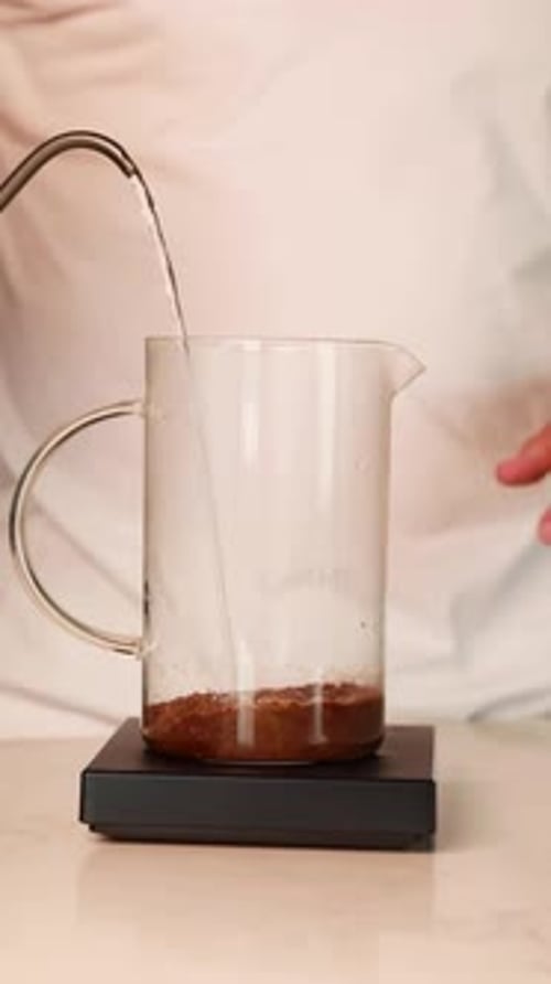 Pouring Water into Coffee Grounds in Glass