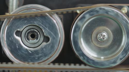 Close up, toothed belt rotating metal pulleys in mechanical system