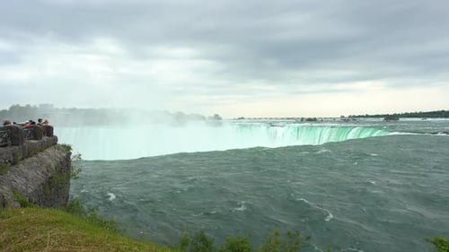 Niagara Falls landscape view over water flowing down the waterfall creating steam, on a cloudy day