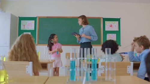 Adorable student learn with teacher in classroom at elementary school.
