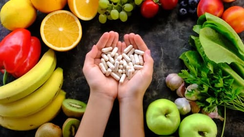 Child Holding Pills Surrounded by Fruits and Vegetables