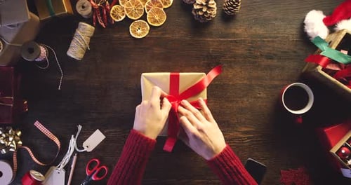 Gift wrap, hands and christmas present with woman and ribbon around box above view