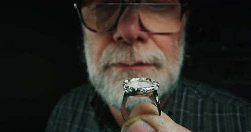 Slow motion of experienced goldsmith controlling a quality of just finished handmade jewelry ring