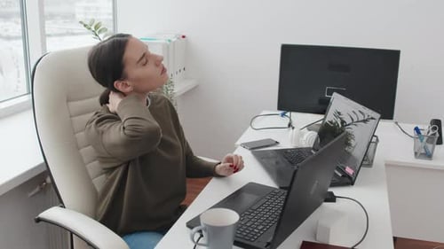 Young Woman Getting Tired From Sitting At Work