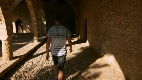 Young man walking among dark ancient rooms in slow motion in cyprus museum