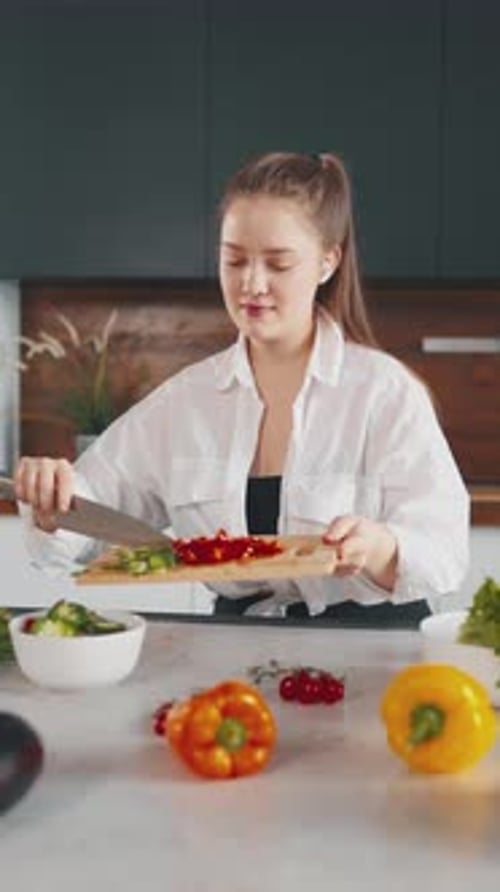 Woman cutting fresh vegetables in modern kitchen