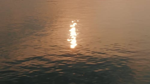 Surface de l'eau de mer au coucher du soleil Une lueur dorée du soleil se reflète sur la surface de la mer au coucher du soleil