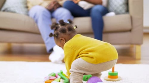 Infant plays with toys at home with family
