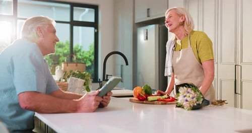 Senior Couple in Kitchen Chatting While Preparing Food