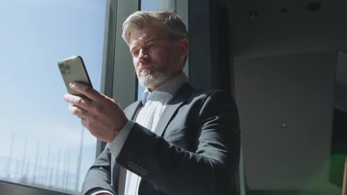 Man Using Phone by Bright Office Window